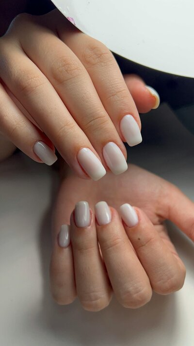 Client’s hands with a fresh, natural nude gel manicure.