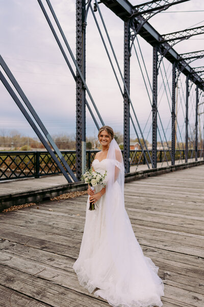 Bride standing on a bridge having wedding portraits done