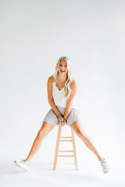 Picture of a girl sitting on a stool and laughing in the studio