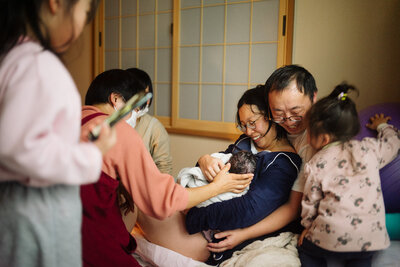 gifu maternity mom sitting on the bed with other two kids.