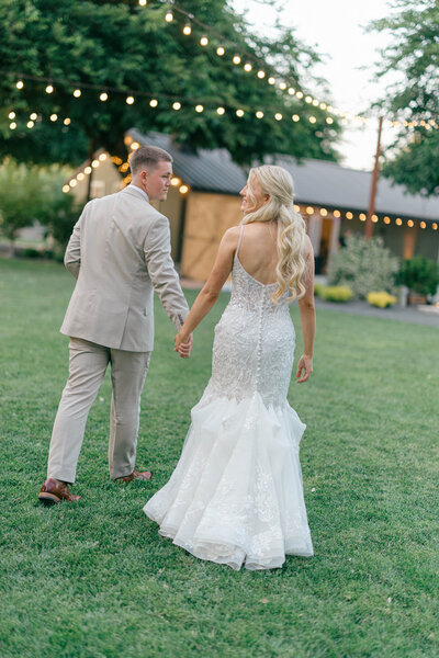 Wedding Photographer for the Bay Area, bride and groom walking together away from camera under strings of lights