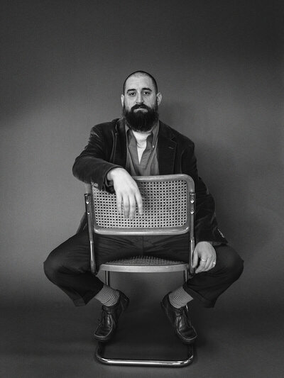 Black and white portrait of a man in a chair, representing the style of Oregon wedding photographer Among the Oaks. 