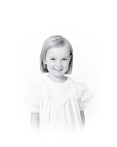 Black and white heirloom portrait of a smiling baby dressed in a classic white outfit with lace details. This timeless baby photography captures the innocence and joy of childhood, created by a Birmingham newborn photographer specializing in elegant, light-filled portraits.