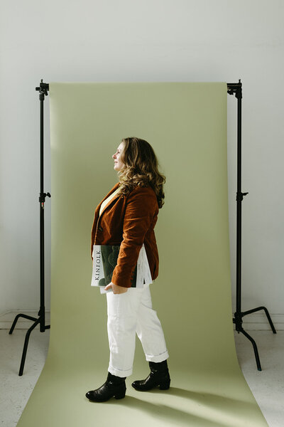 Sara Dobbins in a red jacket and white pants stands in front of green backdrop