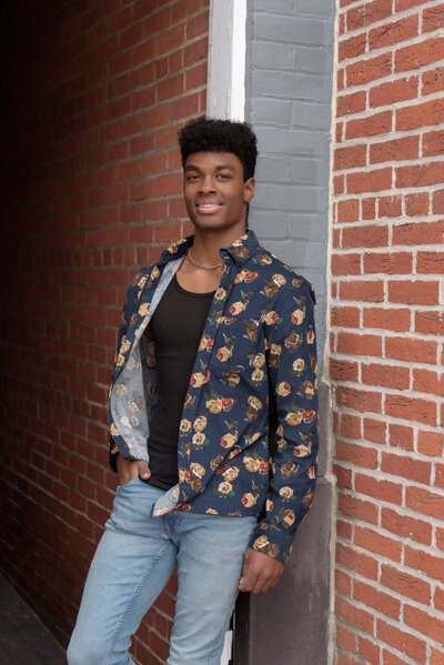 Senior photos of a guy in downtown Harrisburg, PA in the doorway of a brick-lined alley.