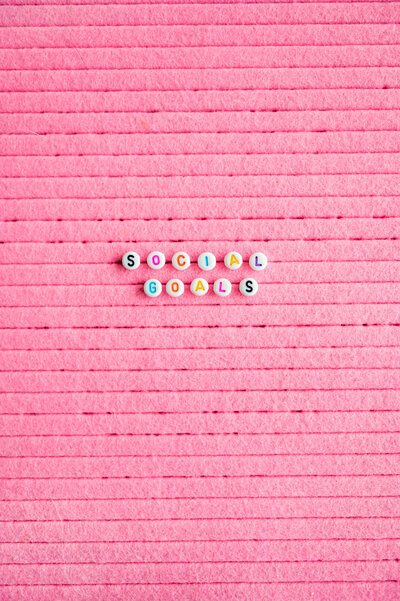Letter beads that spell out Social Goals laying on a pink background