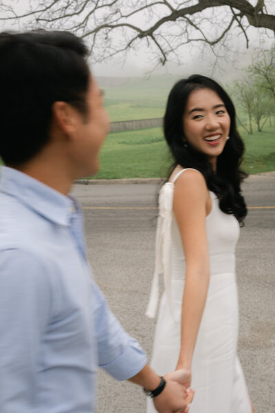 Artistic photo of couple walking and smiling at each other while walking in Niagara on the lake