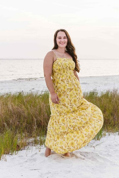 Woman in yellow dress twirls on the beach