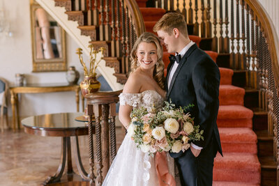 Wedding Photographer, a bride and groom stand together at the bottom of a staircase