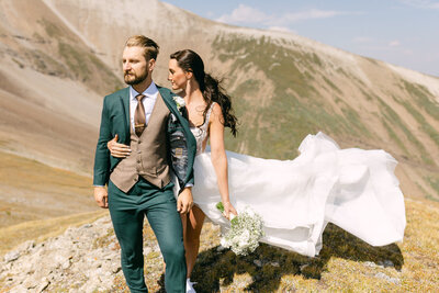 This breathtaking photograph captures the bride looking away during her helicopter elopement portrait session at Mount Charles Stewart. The dramatic mountain landscape enhances the sense of adventure and beauty, making for an unforgettable and epic moment in her wedding experience.