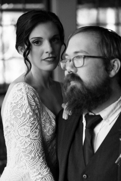 Bride looking to the camera while holding onto her husband at Hawksdene wedding venue in North Carolina, by Andrea-Marie Photography