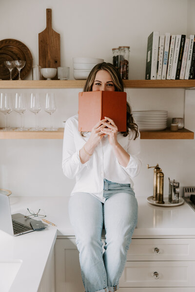A website copywriter sitting on a kitchen counter holding a notebook