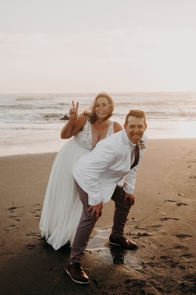 Moving GIF of a bride going in for a kiss with her groom as they sit on a rock next to a lake