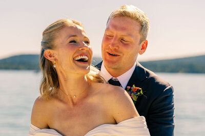 Bride and groom sharing a joyful moment in the sun during their Whitefish Lake Montana wedding, with soft light and natural smiles capturing the emotion of the day.
