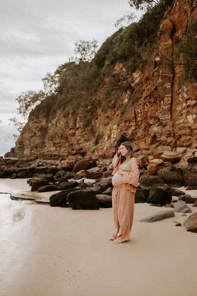 pregnant woman on the beach in front of rocks