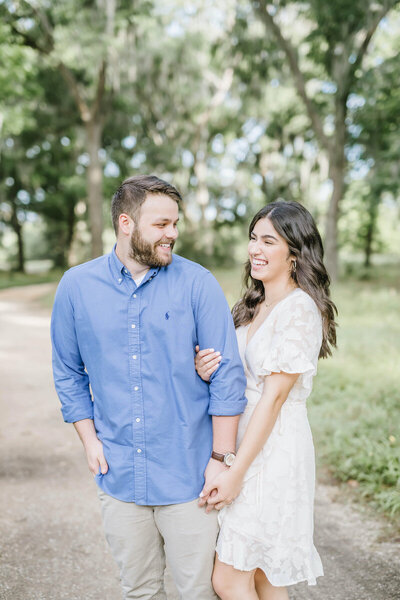 Engaged couple holds hands and smiles during engagement portrait session