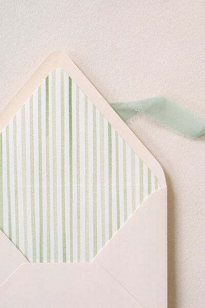 Green striped envelope liner in a blush pink envelope. Photo by Lavender & Light Photography