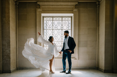 bride and groom standing in front of a window at San Francisco City Hall