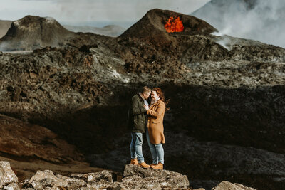 Fairytale newly wed couple is kissing in a cave with a waterfall and sparkly light coming through the cave in Iceland on their elopement day