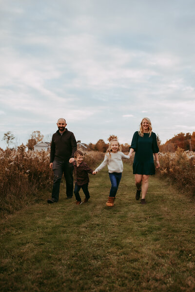 Family photographer capturing amom and dad hold baby girl, mom kisses baby on the cheek
