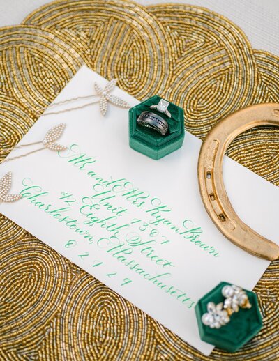 Flatlay featuring calligraphy invitation with green ink and gold accents