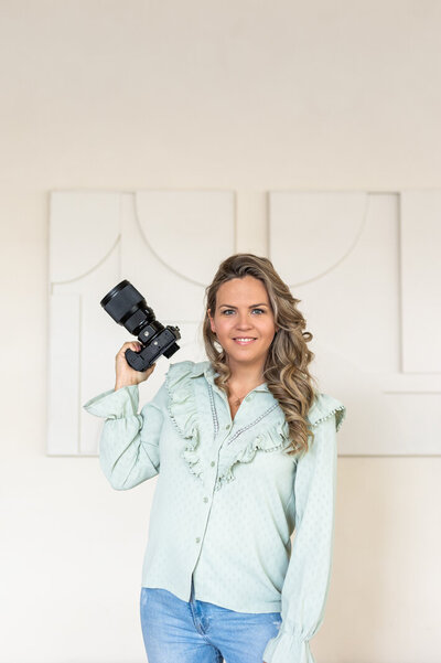 Juliette Laurant van Juliette Fotografie Academy met camera in haar hand lachend.