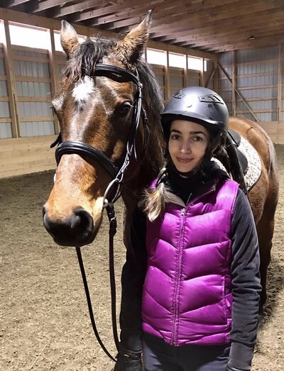 Woman and Horse in riding gear standing in indoor arena. 