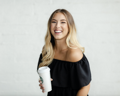 black dress holding coffee laughing