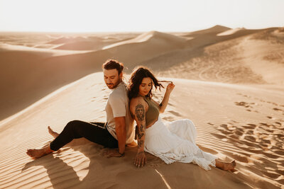 couple sitting in sand dunes