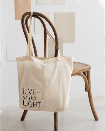 Canvas tote bag mockup with custom branding design reading ‘Live as the Light’ for a spiritual coach.