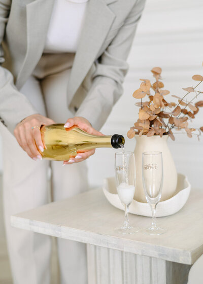 Close-up of a woman pouring champagne into 2 glasses