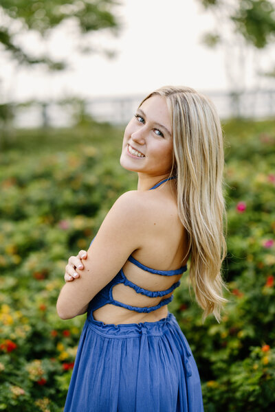 Senior girl smiles over shoulder on the beach in Newburyport, Massachusetts