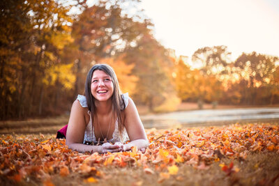 Senior Girl laying on leaves and smiling at Bible Park