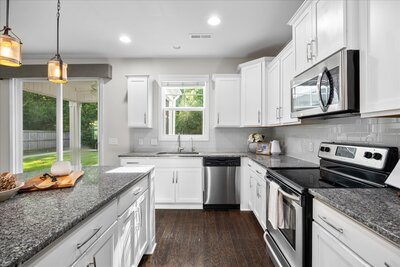 Bright and modern kitchen featuring white cabinetry, granite countertops, and stainless steel appliances