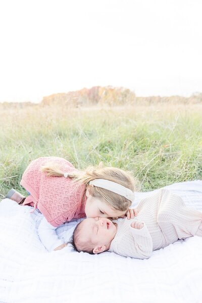 sister kisses baby duirng outdoor newborn photo session at Cow Common in Wayland Massachusetts with Sara Sniderman Photography