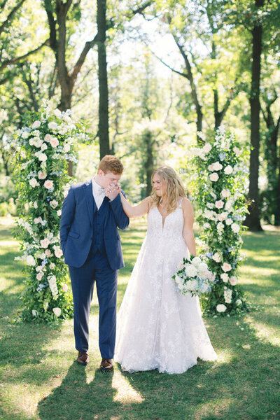 couple kissing in front of flower arch