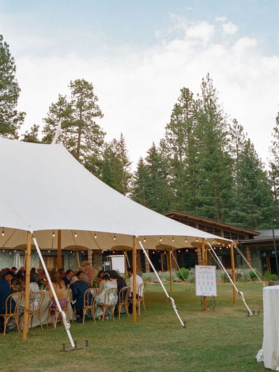 A Sperry Tent stands elegantly beneath the daylight, its sailcloth canopy sheltering tables set for celebration—an inviting scene of natural light, refined details, and open-air romance.