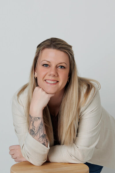 kate mccord, harrisburg photographer, smiling in a tan jacket  on a white background