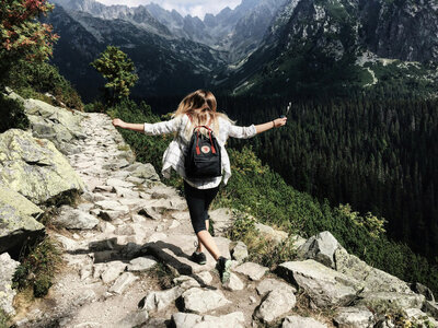 Woman playfully skipping as she hikes a mountain