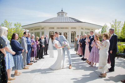 groom in a gray suit leaning in to kiss bride in flowy lace dress after lds temple wedding ceremony