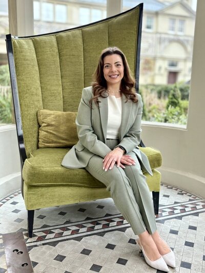 Luisa sits on a chair in an Essex wedding venue ready for you to get in touch about your big day.