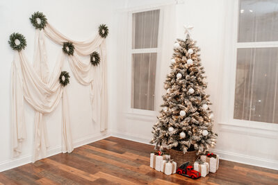 Mother is letting son smell a flower, while daughter stands next to them picking a flower