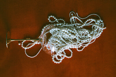 A glass full of pearls on red backdrop.