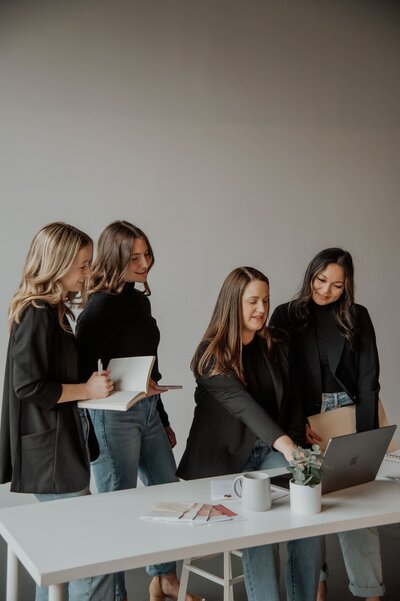Four women talking over a desk looking at a laptop