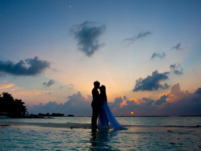 Bride and groom hugging each other in the ocean with sunset