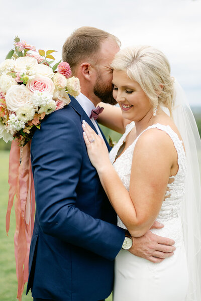 girl in white dress with flowers hugging and smiling at a man in a blue suit