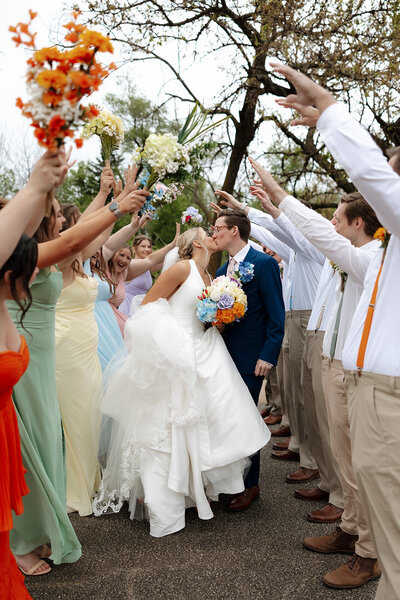 A bride and groom kissing in the middle of their wedding party at a park in Kingman Kansas.