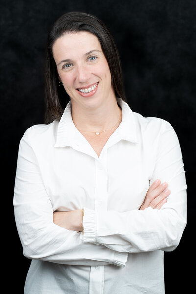Headshot of a business woman wearing a white blouse, arms crossed