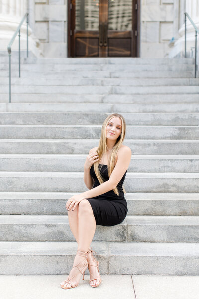 young woman sitting on steps in a black dress