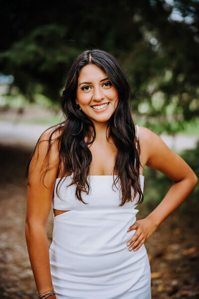 Senior girl in a white dress puts hand on hip